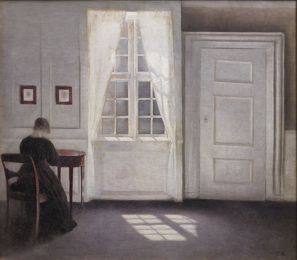 Vilhelm Hammershoi's 1901 painting, "Room in Strandgade with Sunshine on the Floor." A quiet, minimal parlor. A woman sits at a modest wooden chair and table in the left side of the canvas, facing awa